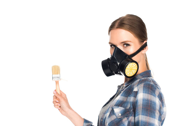 Beyaz arka plan üzerinde izole boya fırçası tutan gaz maskesi genç kadın  - Fotoğraf, Görsel
