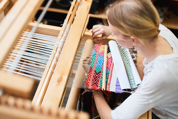 professional blonde woman weaving by hands on old wooden loom - Foto, Imagen