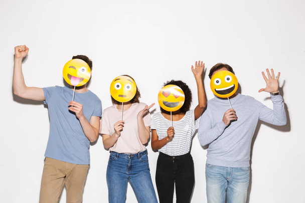 Group of happy multiracial people holding smiley faces isolated over white background - Фото, зображення