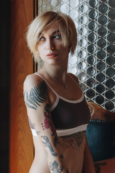 beautiful tattooed woman in underwear looking away indoors - Zdjęcie, obraz