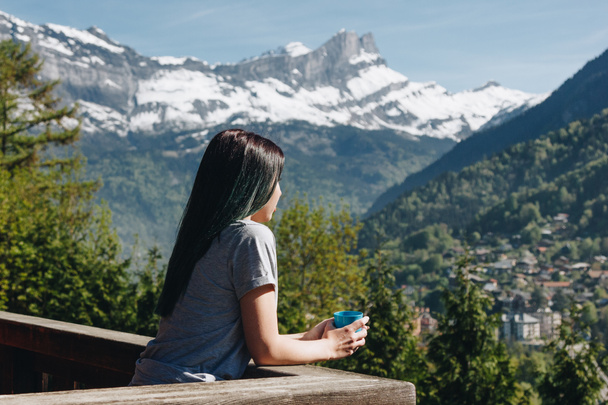 lány holding kupa, miközben erkéllyel állt, és nézte a festői hegyek, mont blanc Alpok - Fotó, kép