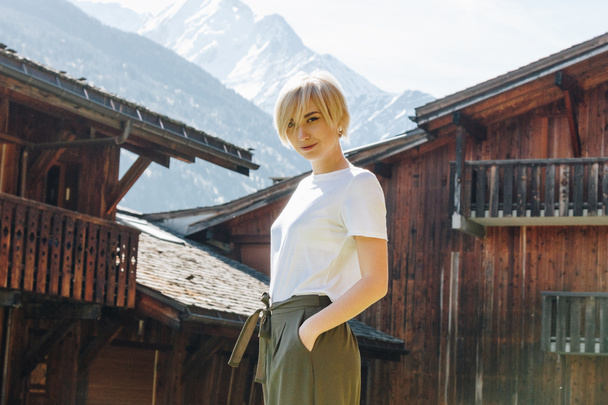 bella felice giovane donna guardando la fotocamera mentre in piedi con la mano in tasca nel villaggio di montagna, mont blanc, Alpi
 - Foto, immagini
