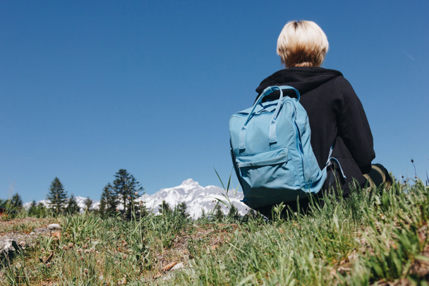 Вид сзади молодой женщины с рюкзаком на траве в горах, Монблан, Альпы
 - Фото, изображение