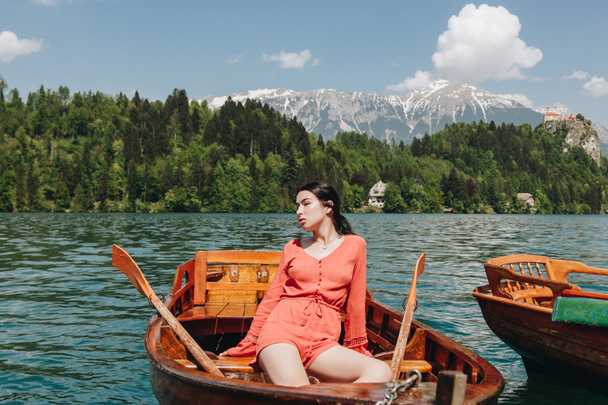 beautiful young woman sitting in boat at scenic tranquil mountain lake, bled, slovenia - Foto, imagen