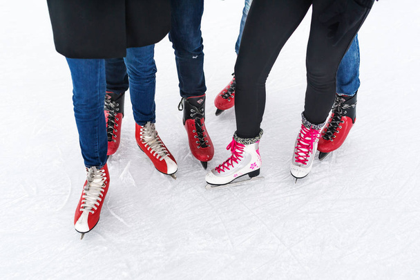 Nahaufnahme von oben auf Beine in modernen Schlittschuhen auf der Eisbahn. Freunde beim gemeinsamen Skaten. - Foto, Bild