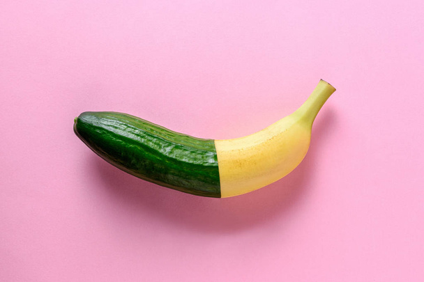 Connected banana and cucumber on pink background. Minimal fruit concept. - Photo, Image