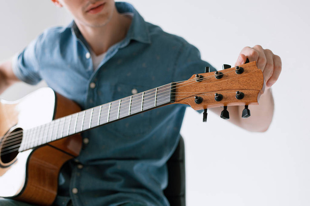Красивый и веселый парень музыкант в футболке, играющий на гитаре
 - Фото, изображение