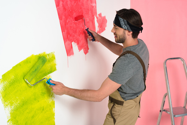 puolella näkymä hymyilevä mies työskentelee yleistä maalaus seinään kaksi maalaustelat
  - Valokuva, kuva