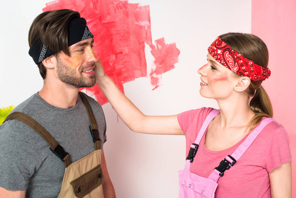vista lateral de la mujer joven en general de trabajo con la cara pintada tocando la cara novio
  - Foto, Imagen
