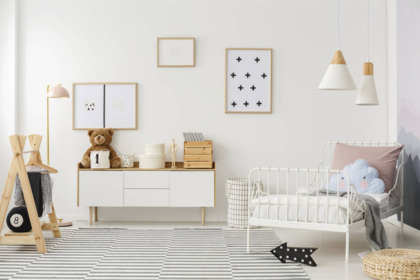Blue pillow on white bed in scandi kid's bedroom interior with mockup of empty poster - Foto, Imagem