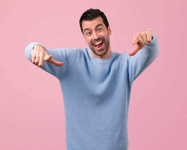 Handsome man pointing with finger at someone and laughing a lot on pink background - Photo, Image