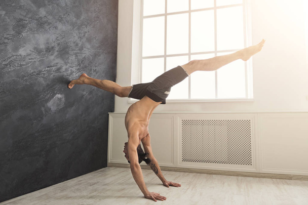 Young man practicing yoga at wall - Photo, Image