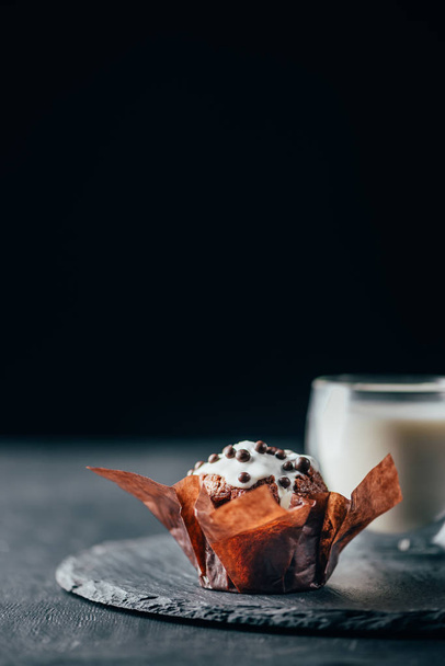 Sweet muffin with chocolate chips and glass of milk on slate board - Fotó, kép