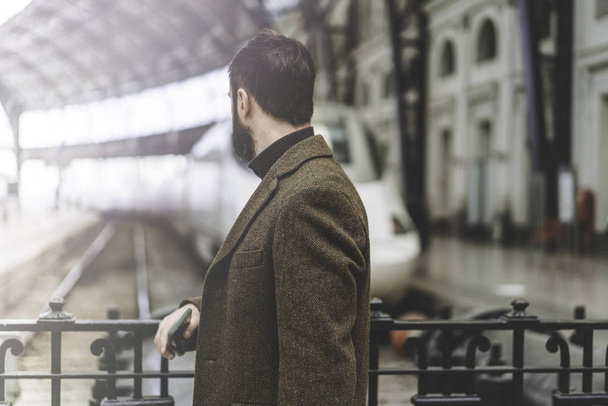 Attractive bearded businessman standing at the hall of railway station and waiting his train.Visual effects. - 写真・画像