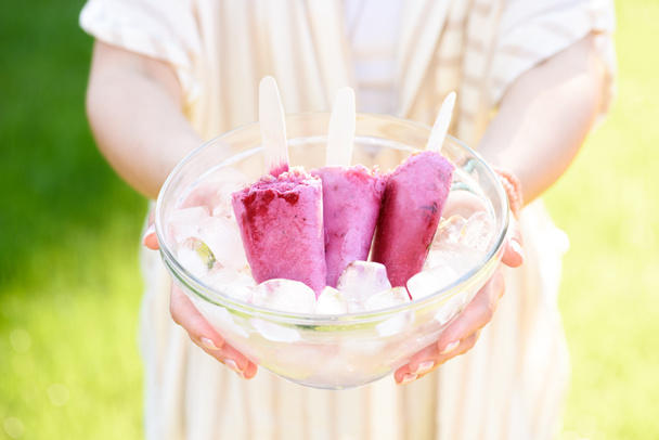 Woman holding bowl with berry ice pops - 写真・画像