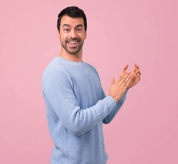 Man with blue sweater applauding after presentation in a conference on pink background - Foto, Bild