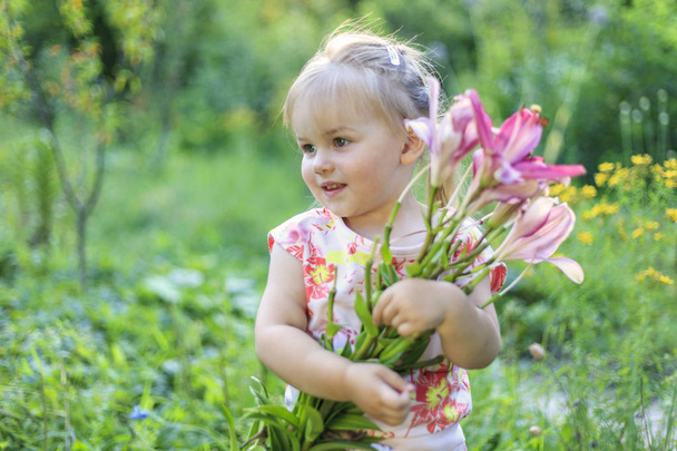 Πανέμορφο λευκό κορίτσι με ένα χαμόγελο και ένα μπουκέτο λουλούδια, - Φωτογραφία, εικόνα
