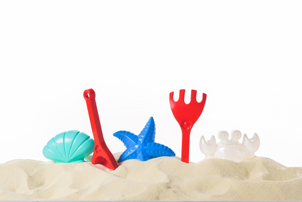 Plastic beach toys in sand isolated on white - Foto, afbeelding