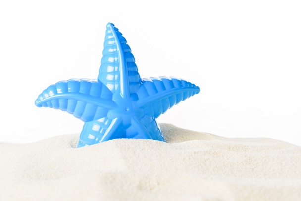 Speelgoed zeester in zand geïsoleerd op wit - Foto, afbeelding