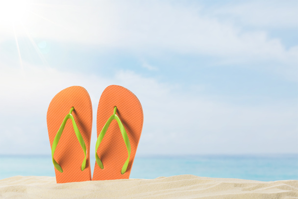 Pair of flip flops in sand on blue sky background - Photo, Image