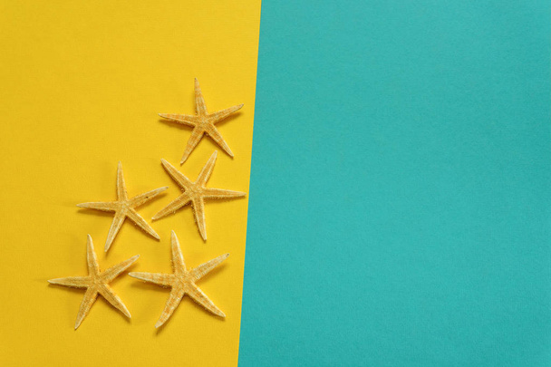 Summer background of yellow and blue paper with starfish, symbolizing the sea coast - Fotoğraf, Görsel