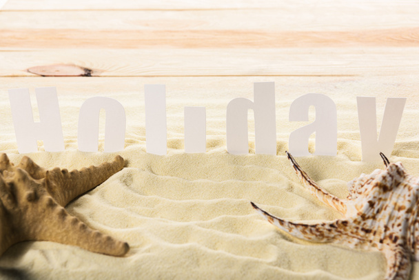 Starfish with seashell and Holiday inscription on sandy beach - Fotoğraf, Görsel