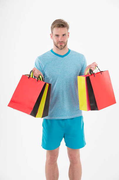 Man with shopping bags isolated on white. Macho with colorful paper bags. Fashion shopper in casual blue tshirt and shorts. Holidays preparation and celebration. Shopping during sale and black friday - Zdjęcie, obraz