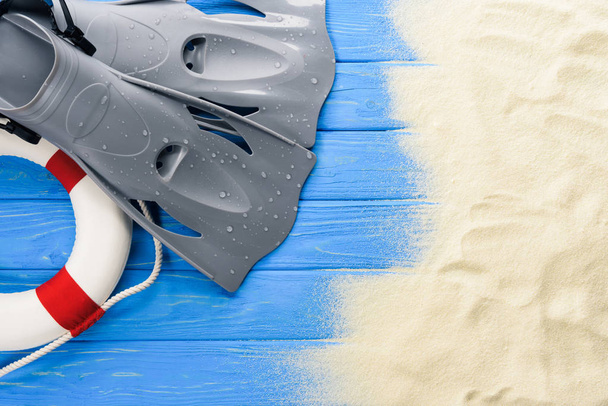 Leven ring en natte flippers op blauwe houten achtergrond - Foto, afbeelding