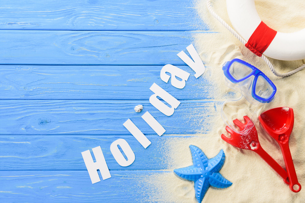 Beach toys and Holiday inscription on blue wooden background - Photo, Image