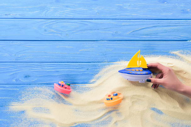Femme jouant avec bateau jouet sur fond bleu en bois
 - Photo, image
