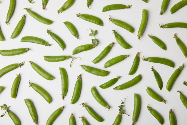 top view of ripe pea pods spilled on white surface - Фото, зображення