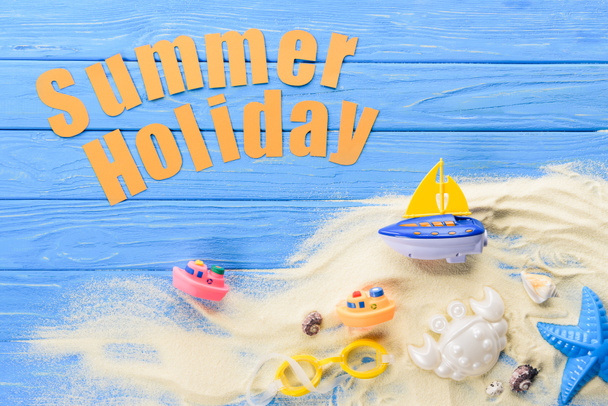 Juguetes de playa por Inscripción de vacaciones de verano sobre fondo azul madera
 - Foto, Imagen