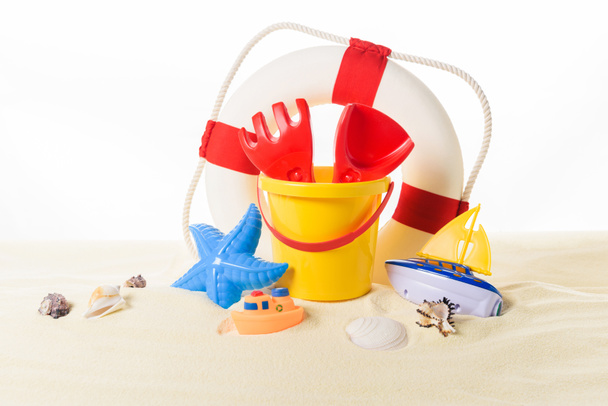 Life ring and beach toys in sand isolated on white - Photo, Image