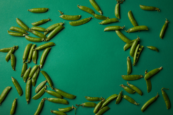 vista superior del marco redondo hecho de vainas de guisante en la superficie verde
 - Foto, Imagen