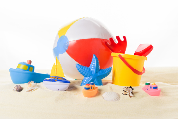 Strandbal en kid speelgoed in zand geïsoleerd op wit - Foto, afbeelding