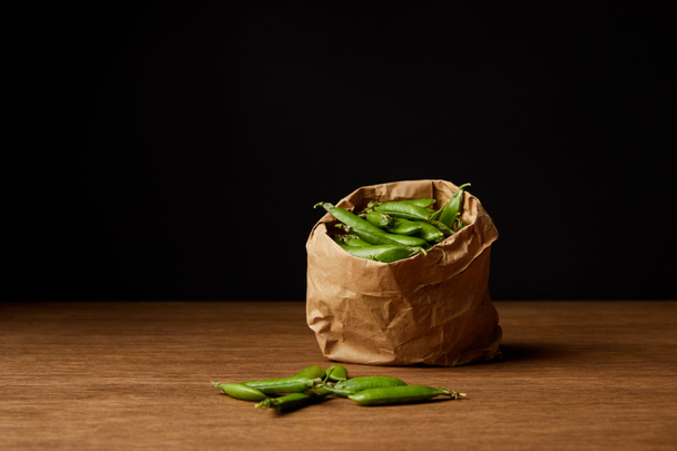 paper bag of pea pods on wooden tabletop - Фото, изображение