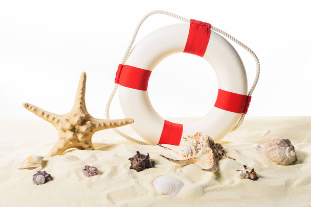 Life ring and seashells in sand isolated on white - Photo, Image