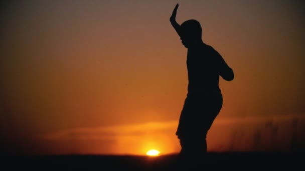 Silhouette d'acrobate mâle effectuant des tours de capoeira sur la colline au coucher du soleil
 - Séquence, vidéo