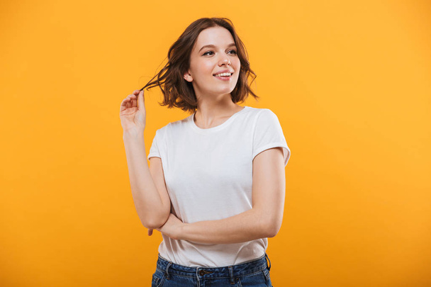 Photo of thinking cute young woman standing isolated over yellow background looking aside. - Foto, Imagen