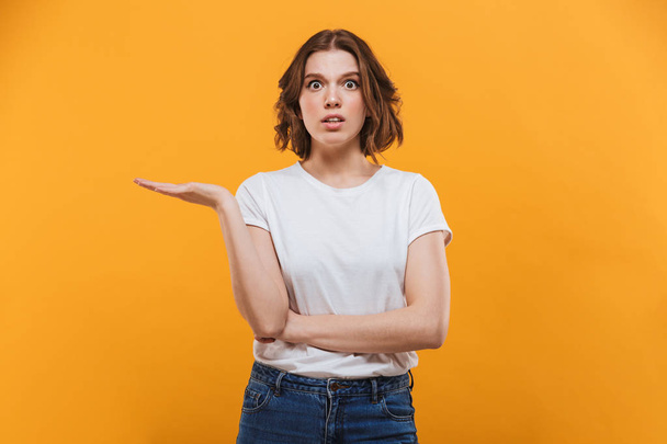 Image of displeased young lady standing isolated over yellow background looking camera. - Foto, afbeelding
