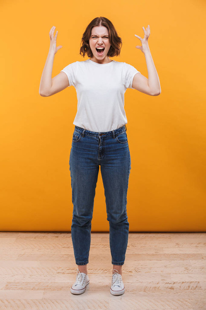 Image of agressive screaming young lady standing isolated over yellow background. - Φωτογραφία, εικόνα