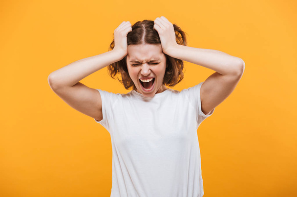 Image of agressive screaming young lady standing isolated over yellow background. - Foto, immagini