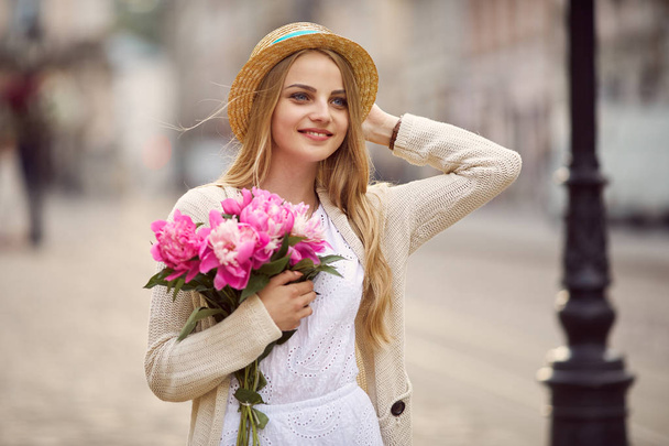Genç sarışın kız pembe çiçekler ve şapka ile - Fotoğraf, Görsel