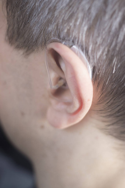 Deaf middle aged man wearing modern digital high technology hearing aid in ear. - Photo, Image