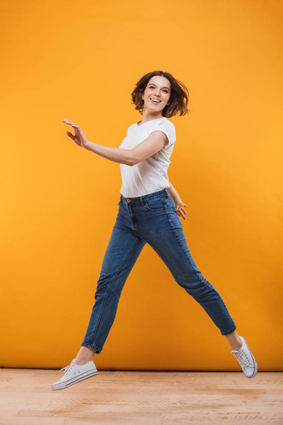 Photo of excited young woman jumping isolated over yellow background. - Photo, Image