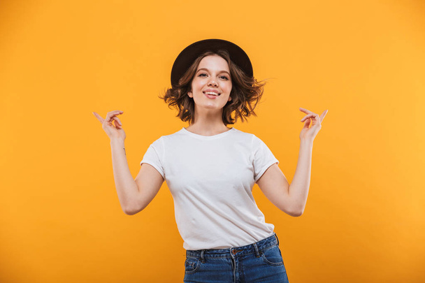 Image of excited emotional young woman standing isolated over yellow background showing copyspace. - Foto, Imagen