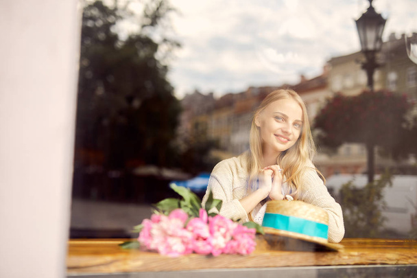 Pretty blonde girl eat her morning smoothie with flowers on the table - Фото, зображення