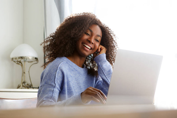 ノート パソコンを見ていると、笑顔の美しい若いアフリカ系アメリカ人女性の肖像画  - 写真・画像