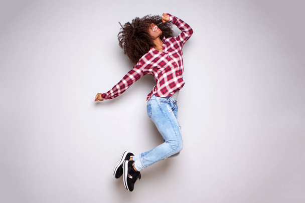 Полный портрет возбужденной молодой женщины, прыгающей в воздухе на белом фоне
 - Фото, изображение