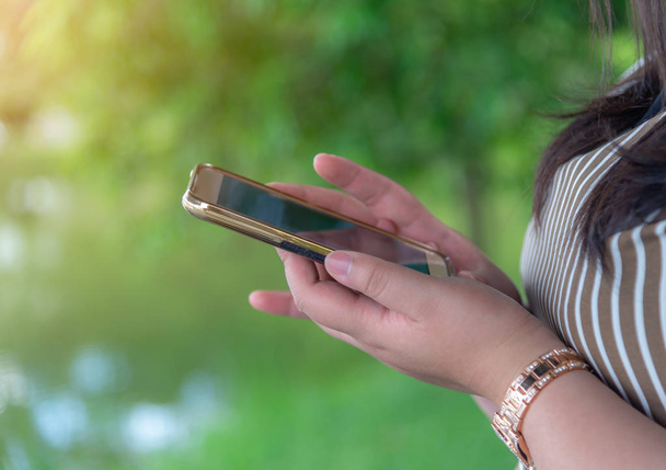 Online alışveriş ve online bankacılık ve internet bankacılık kavramı, akıllı telefon üzerinde hareket eden kadınlarla el bokeh doğa arka plan bulanık - Fotoğraf, Görsel